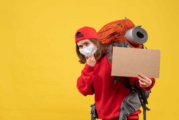 硬纸板前视图旅行女孩与背包和面具举行纸板面具手持背包