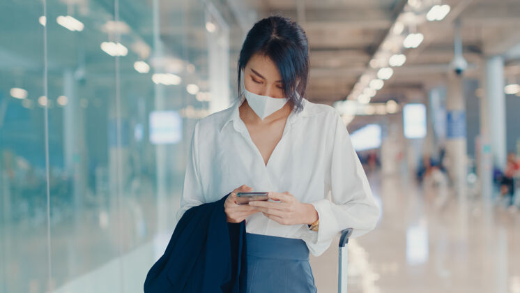 通讯亚洲商务女孩用智能手机检查登机牌 带着行李到机场国内航班的候机楼手机女性公司