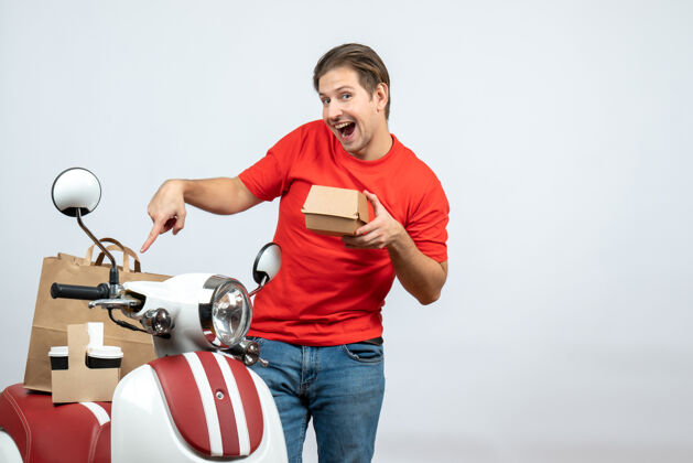 运动员身穿红色制服的送货员站在踏板车旁 展示白色背景的小盒子运动运动装活跃