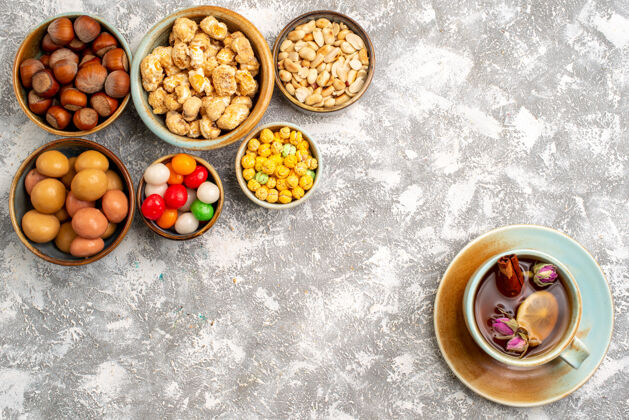 食用坚果榛子和花生的俯视图 白色表面上有糖果和一杯茶午餐种子蔬菜