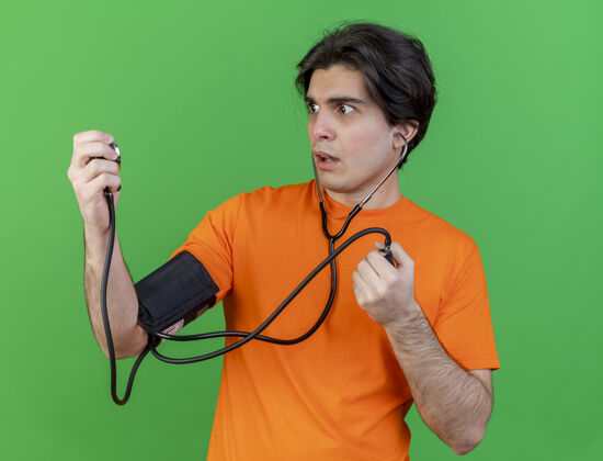 血压计关心的年轻病人用隔离在绿色墙上的血压计测量自己的血压绿色年轻自己