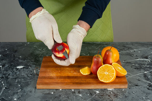 厨师男手在桌上的木板上剥红苹果围裙切片手
