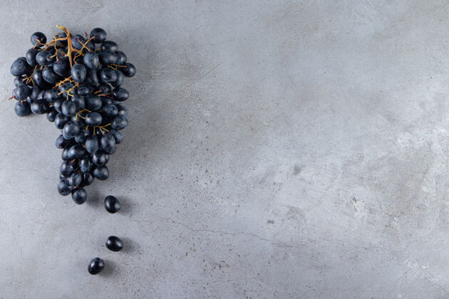 葡萄一簇新鲜的黑葡萄放在石头背景上食品多汁黑色