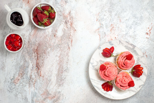 饼干白色表面有果酱和巧克力棒的粉色草莓蛋糕俯视图鲜花棒茶