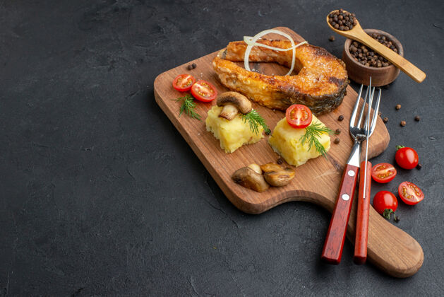 午餐侧视图美味的炸鱼和蘑菇西红柿绿色的木制砧板餐具集胡椒粉在黑色的表面晚餐番茄美味