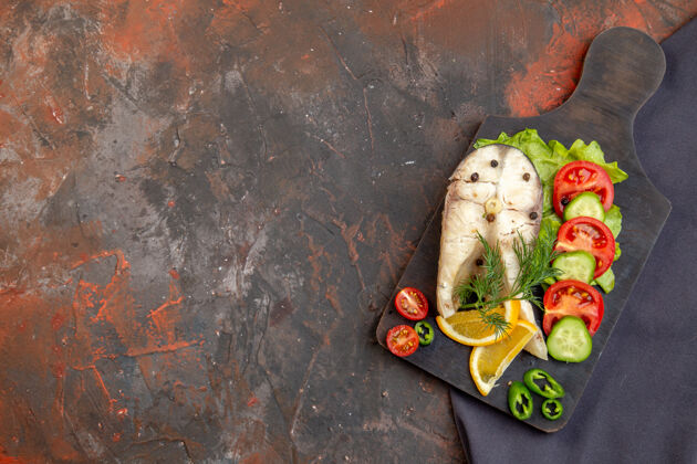 餐厅在混合色表面上的深色毛巾上的黑色切割板上的生鱼和胡椒新鲜食物的俯视图切割顶部晚餐