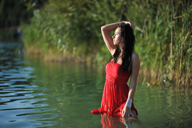 女人夏天的年轻女子红色长裙在户外摆姿势性感人时髦