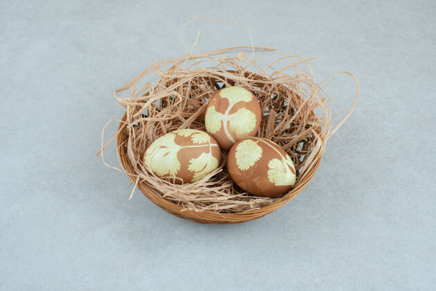 鸡蛋在柳条篮子上的干草里画了三个鸡蛋美味食物五颜六色