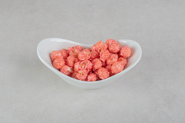 爆米花在大理石桌上的椭圆形碗里提供红色爆米花糖果的小吃服务小吃牙齿