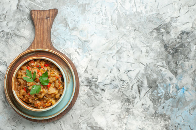 餐盘灰色表面上砧板上碗里烤茄子沙拉的俯视图香料胡椒木勺