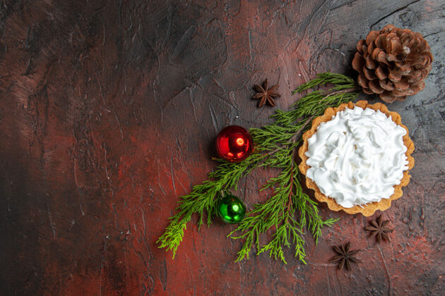 庆典小馅饼的顶视图 在深红色的表面上有八角星 小枝 松果和圣诞球冬天装饰品球