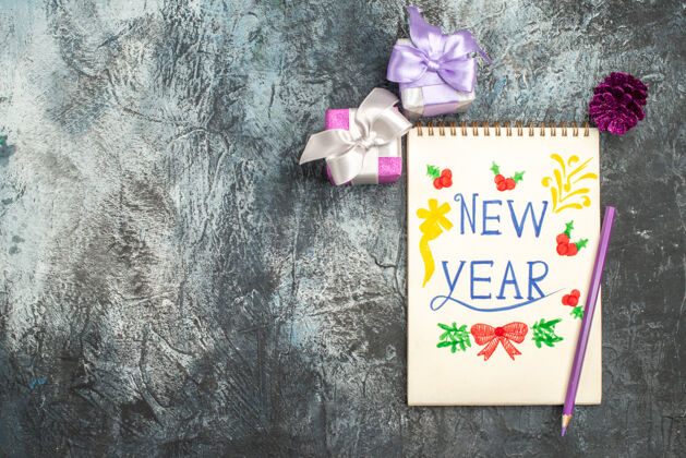 学校用铅笔和小礼物在灰色表面的新年笔记俯视图礼物容器节日
