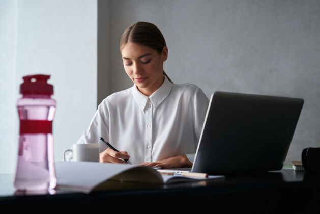 工作专心工作的女人在家里用笔记本电脑坐着笔记本电脑年轻