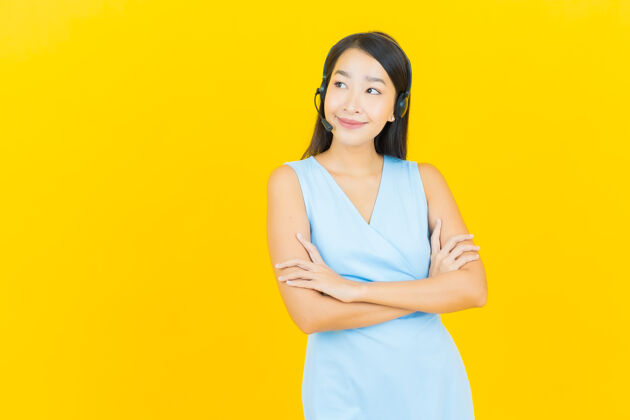 客户在黄色的墙上画上一幅美丽的亚洲年轻女子与呼叫中心客户服务中心工作年轻人解决方案