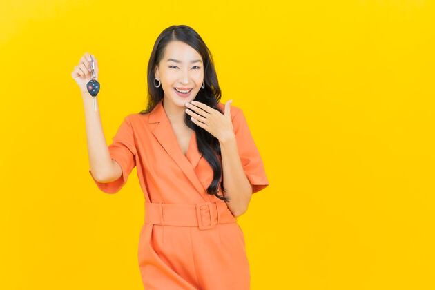 保险肖像美丽的亚洲年轻女子微笑着把车钥匙放在黄色女人亚洲人业主