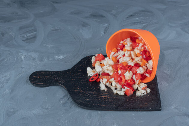 可口胡椒和花椰菜沙拉从碗里倒出来 放在大理石桌上的黑木板上美味饮食美味