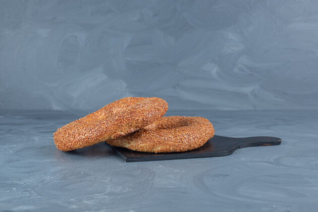 外套酥脆的芝麻面包圈放在大理石桌上的木板上酥脆美味可口