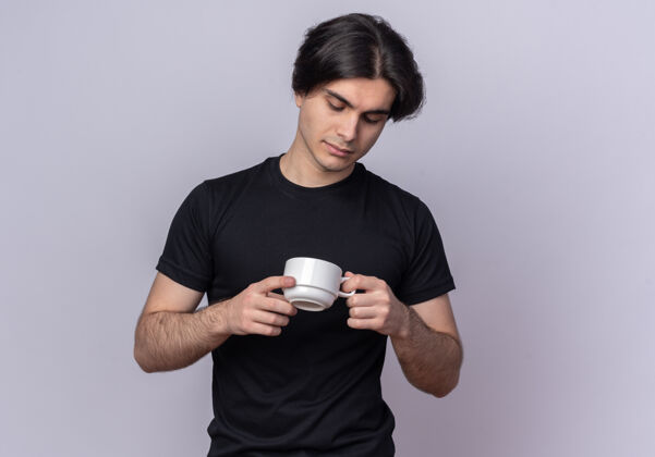 思考想着那个穿着黑色t恤的年轻帅哥 捧着一杯咖啡 看着隔离在白墙上的咖啡抱着年轻咖啡