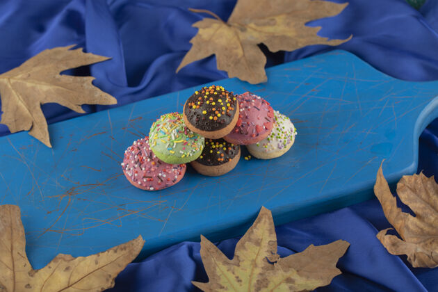 面团蓝色木板上五颜六色的甜甜圈各种甜甜圈食物