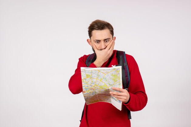 成人正面图年轻男性游客背着背包探索地图白墙飞机城市度假情感人文旅游探索城市情感