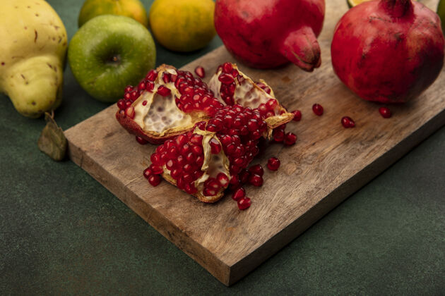 食品木制厨房板上的多汁石榴俯视图 苹果和木瓜相互隔离石榴绿色木材