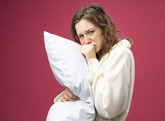 咳嗽咳嗽的年轻病女孩直直地向前看穿着白色长袍抱住枕头孤立在粉红色枕头疾病年轻