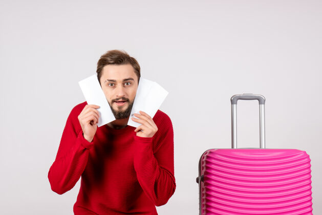 颜色正面图：年轻男性 带着粉色包 手持白墙航班彩色旅游度假的机票游客微笑肖像