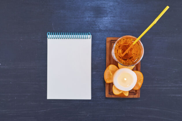 酒精橘子和一杯果汁 黄色的管子放在木制盘子上 白色的笔记本高质量的照片刷新鸡尾酒冷