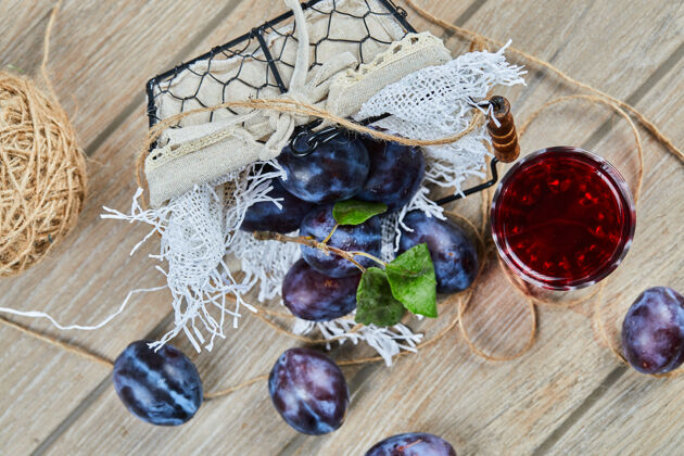 浆果花园李子在一个篮子里放在一张木桌上 桌上放着一杯果汁高质量的照片自然有机收获
