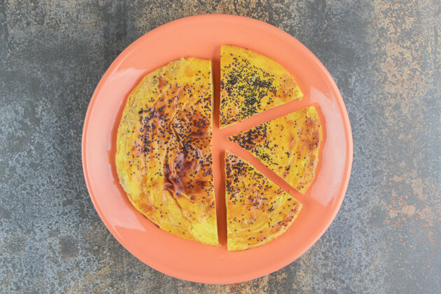 碎在橙色盘子上放着的圆形糕点派平铺罂粟