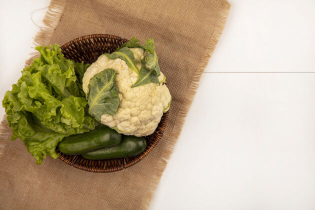 袋子顶视图新鲜蔬菜 如莴苣 花椰菜和黄瓜在一个桶上的一个白色背景袋布与复制空间观点食物桶
