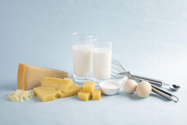 乳制品拍摄一个美味的奶酪拼盘与牛奶和鸡蛋隔离在淡蓝色的背景玻璃切片蓝色