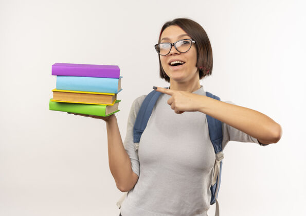 戴印象深刻的年轻女学生戴着眼镜 背着书包拿着书 指着孤立的白色指学生眼镜