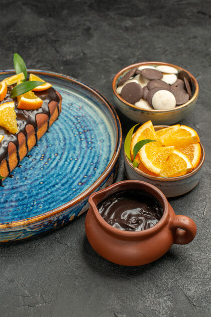 水果美味的蛋糕装饰着橘子和巧克力与其他饼干在黑暗的桌子镜头深色碗饼干