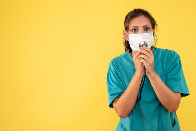 视图正面图黄色背景上穿着医用衬衫和带听诊器面罩的女医生病毒医疗呼吸装置