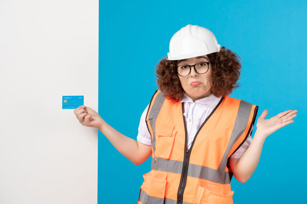 女蓝色墙上穿着制服戴着头盔的女建筑工人的正视图人承包商建筑工人