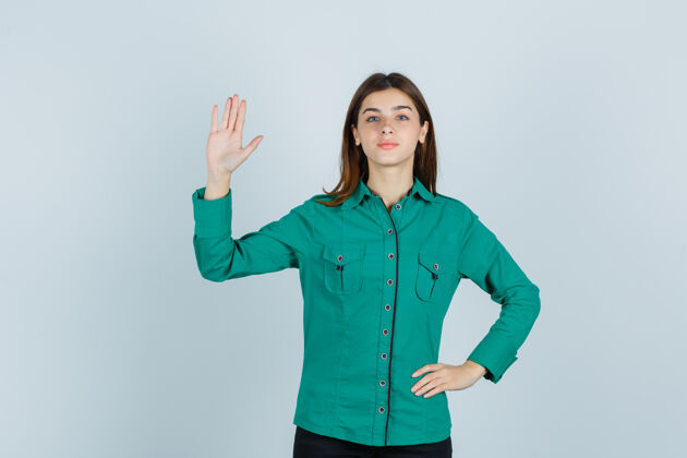 女士身穿绿衬衫的年轻女士展示手掌 看起来很自信 正面视图年轻人物模特