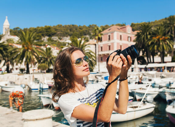 微笑迷人的女人在欧洲海边度假 在游轮上用相机拍照旅游有趣阳光