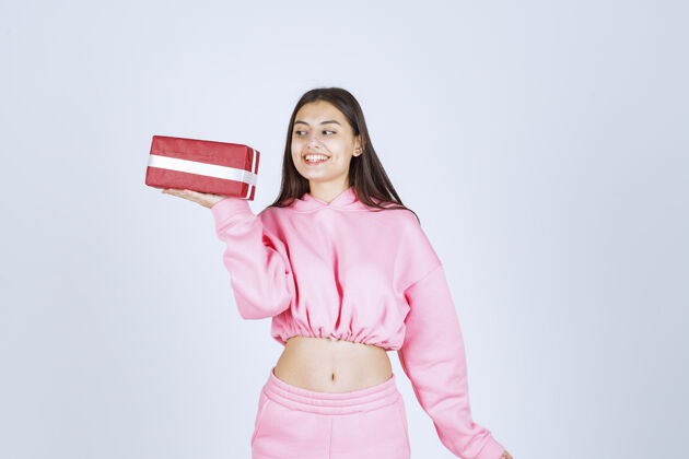 姿势穿着粉色睡衣的女孩手里拿着一个红色长方形礼盒 看上去很满意积极人类人体模型