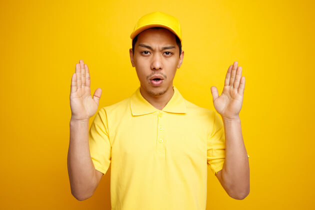 皱眉皱眉的年轻送货员戴着帽子和制服做着大小手势黄色男人手势
