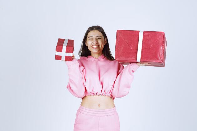 员工穿着粉色睡衣的女孩拿着大大小小的红色礼盒 微笑着女性人欢乐
