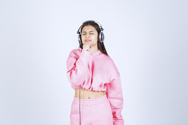 姿势穿着粉色睡衣的女孩在听耳机 不喜欢音乐高质量的照片模特工人娱乐