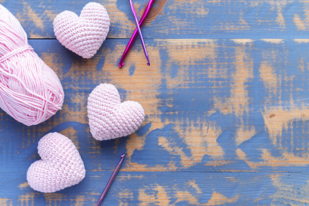 开花手工编织的三个粉红色的心与纱球俯视图组成形状自制