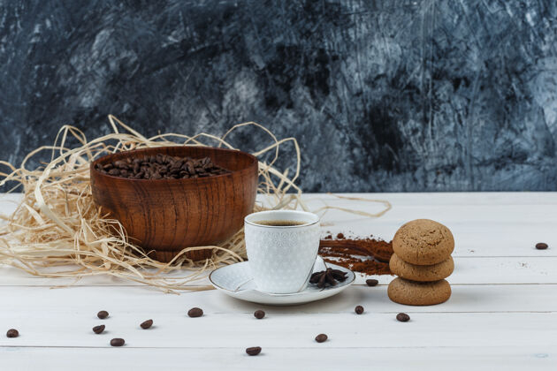 桌子咖啡在一个杯子与研磨咖啡 咖啡豆 香料 饼干侧视图在木制和垃圾的背景杯子咖啡馆质地