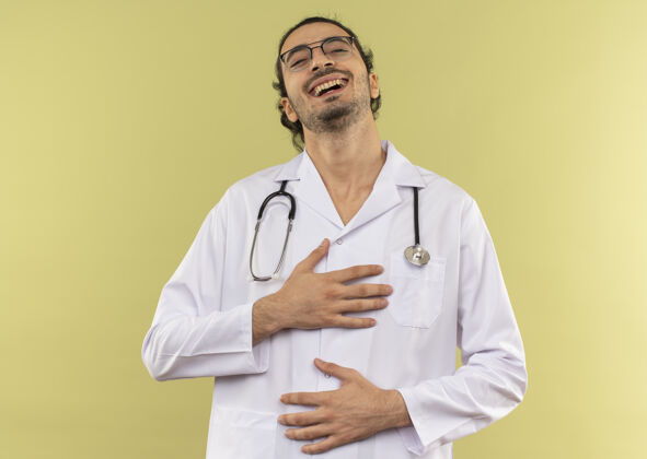 胃年轻的男医生 戴着眼镜 穿着白色长袍 听诊器 双手放在胸部和腹部笑男性绿色