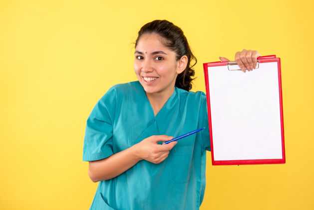 医学前视图快乐的年轻女性拿着剪贴板和黄色背景上的笔球员信心成人