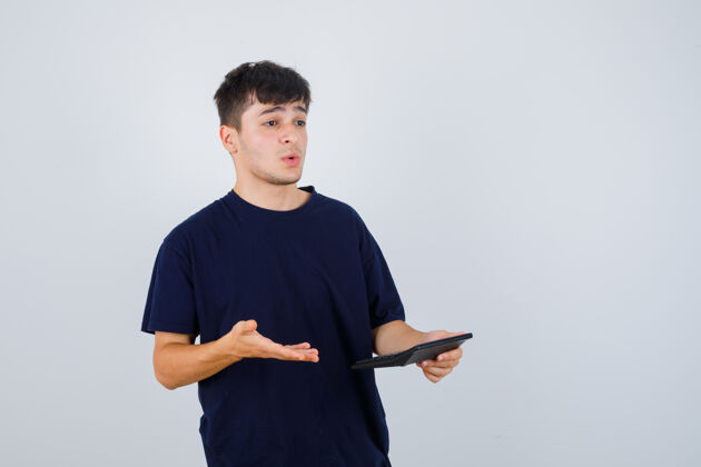 男人一个年轻人拿着计算器 穿着黑色t恤衫 看上去很困惑 正对着前方英俊人表情