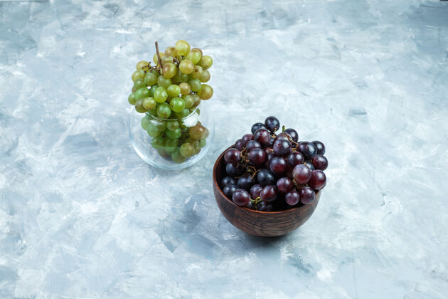 季节葡萄串在粘土碗和玻璃罐高角度看一个肮脏的灰色背景罐食物粘土