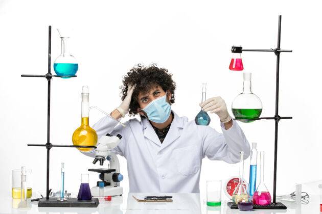 科学前视图男性化学家 穿着白色医疗服 戴着面罩 在浅白的空间里拿着蓝色溶液医生外套实验室