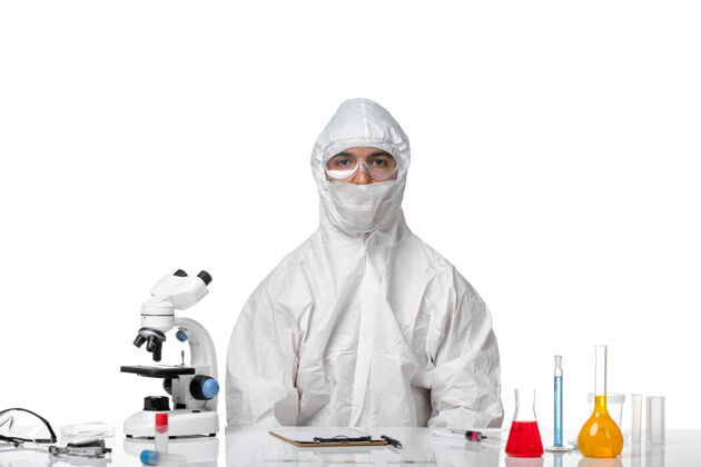 工作人员正面图：男医生穿着防护服 戴着口罩坐在白色的桌子上医疗药品大流行